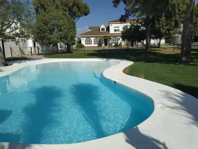 a swimming pool in a yard with a house in the background at Hacienda Laguna Seca - Apart. Hibisco in Chiclana de la Frontera