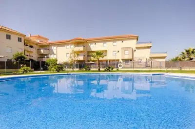 a large blue swimming pool in front of a building at ÁTICO BAJO GUÍA in Sanlúcar de Barrameda