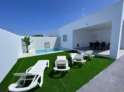 a room with white chairs and a table and grass at GRANIZO B in Chiclana de la Frontera