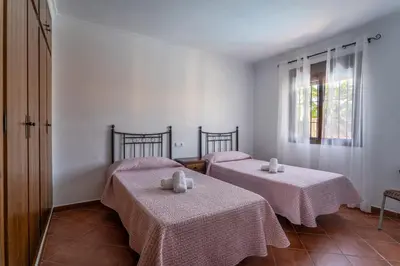 two beds in a room with white walls and a window at EntreCalas 3 chalet piscina privada Conil, Roche Viejo, Cala del Aceite in Conil de la Frontera