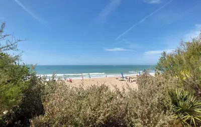 a beach with people sitting on the sand and the ocean at Gorgeous Home In Chiclana De La Fronter in Chiclana de la Frontera