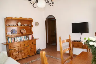 a living room with a television and a wooden dresser at Caracola Wohnung in Chipiona