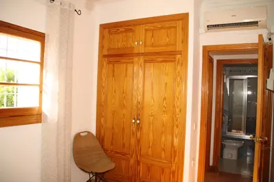 a wooden cabinet in a room with a window and a chair at Caracola Wohnung in Chipiona