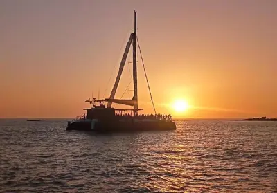a boat with people on it in the water at sunset at Cozy Apart. Costa Sancti Petri by Chiclana Dreams in Novo Sancti Petri