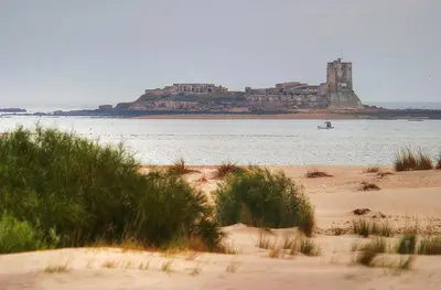 a view of a beach with a castle in the water at Apartamento Costa de Sancti Petri by Chiclana Dreams in Novo Sancti Petri