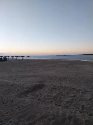 an empty beach with umbrellas in the distance at PLAYA LAS PILETAS-CALZADA in Sanlúcar de Barrameda
