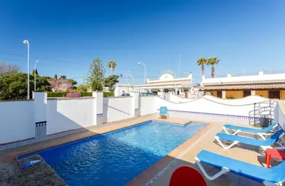 a swimming pool with two lounge chairs and a house at Apartamento Casa Postas II in Conil de la Frontera