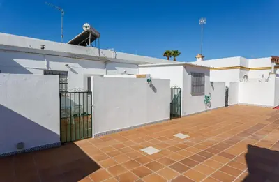 a white building with a gate and a tile courtyard at Apartamento Casa Postas II in Conil de la Frontera