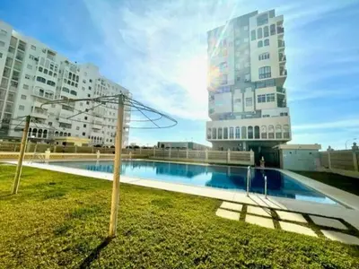 a swimming pool in front of two tall buildings at GATU DULCE junto playa, terraza, aire acc, parking, piscina , 