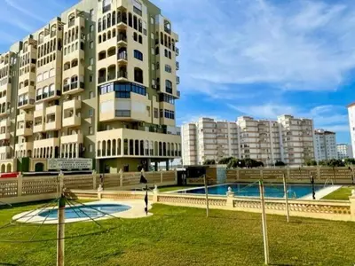 a large building with a pool in front of it at GATU DULCE junto playa, terraza, aire acc, parking, piscina , 