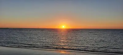 a sunset on the beach with the sun setting at Apartamento JARDINES DE BAJO GUIA in Sanlúcar de Barrameda
