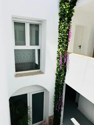 a white building with a window with purple flowers at Sotavento Malandar in Sanlúcar de Barrameda