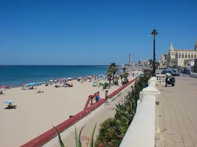 a group of people on the beach near the ocean at Apartamento Caracola in Chipiona