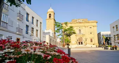 a building with a clock tower and flowers in front of it at Casa Chiclana Centro in Chiclana de la Frontera