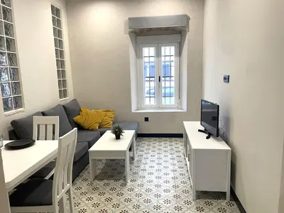 a living room with a couch and a tv at Apartamento Plaza del Cabildo II - Sanlúcar Centro in Sanlúcar de Barrameda