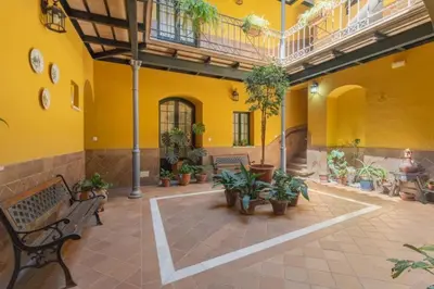 a courtyard with benches and potted plants in a building at Rincón Centro exclusive in Jerez de la Frontera