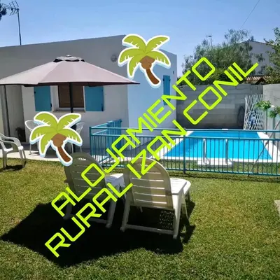 a pair of chairs and an umbrella in the grass at Casa MARINERA in Cádiz
