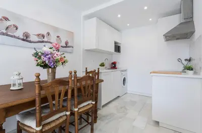 a kitchen with a wooden table and chairs at Vistahermosa 2 Rooms Piscina in El Puerto de Santa María