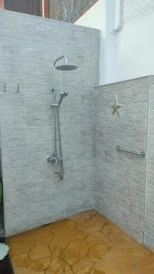 a shower in a bathroom with a stone wall at Apartamento Pacífico in Chipiona