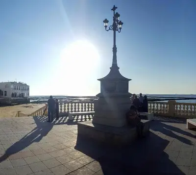 a person sitting on a bench next to a statue at La Marea in Chipiona