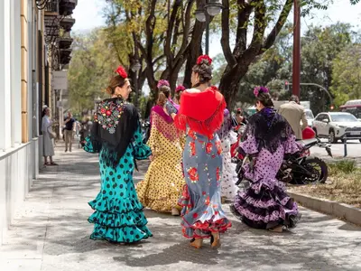 four women in colorful dresses walking down a sidewalk at Descubre El Puerto de Santa María desde el corazón de su casco histórico in El Puerto de Santa María