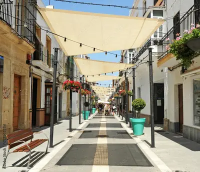 an empty city street with benches and buildings at Apartamentos Patio Andaluz El pozito in Rota