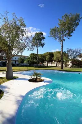 a swimming pool with blue water in a park at Hacienda Laguna Seca - Apart. Lavanda in Chiclana de la Frontera