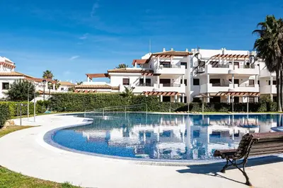 a swimming pool with a bench in front of a building at coto 8 22 in Chiclana de la Frontera