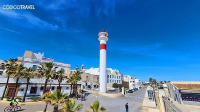 a lighthouse in the middle of a street with palm trees at Apartamento patio Andaluz in Rota