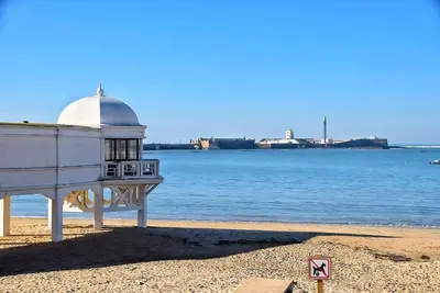 a building on the beach next to the water at Apartamento Luz de Cádiz in Cádiz