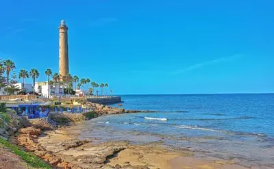 a lighthouse on the shore of a beach at YourHouse Apartamentos Andasol 1 I in Chipiona