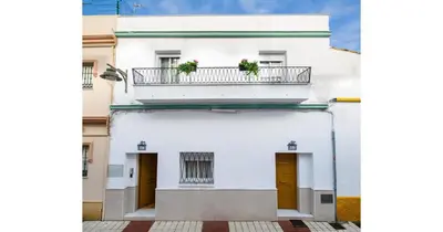 a white building with a balcony with two plants on it at YourHouse Apartamentos Andasol BB in Chipiona
