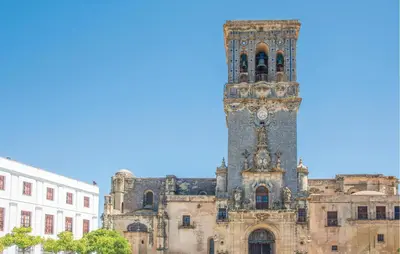 a building with a tower with a clock on it at 1 Bedroom Nice Apartment In Arcos De La Frontera in Arcos de la Frontera
