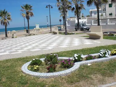 a beach with a lighthouse and people on the beach at Apartment Penthouse- Klimatisierung- Strand und Sonne das ganze Jahr über by Interhome in Chipiona