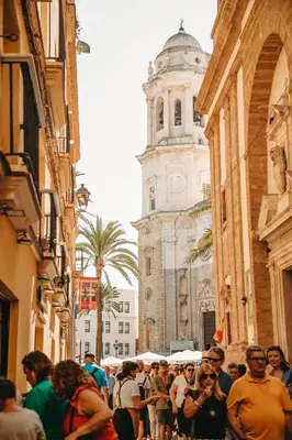 a crowd of people walking down a street with a clock tower at Hidden Gem CADIZ BEACH LOFT by Apartmentsincadiz in Cádiz