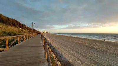 a wooden boardwalk leading down to the beach at Duplex El Manantial in El Puerto de Santa María