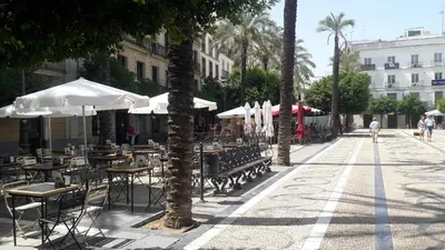 an empty street with tables and chairs and umbrellas at Sherryflat Caballeros - Parking in Jerez de la Frontera