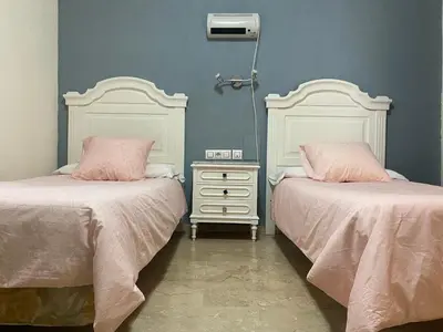 a bedroom with two beds and a nightstand with pink pillows at Hotel Medina Centro in Jerez de la Frontera