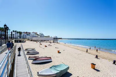 a beach with chaise lounges and boats on it at Apartamento SERAFÍN de la Caleta in Cádiz
