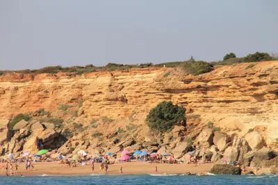 a group of people on a beach with umbrellas at Apartamento en complejo con piscina in Conil de la Frontera