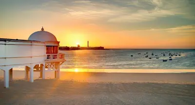 a lighthouse on the beach with people in the water at Casa Rural Vacacional in Puerto Real