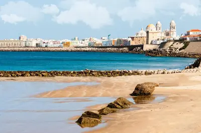 a beach with rocks and buildings in the background at San Francisco 15 in Cádiz
