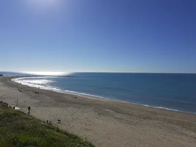 a beach with people walking on the sand and the ocean at Los Balcones de Cádiz in Cádiz