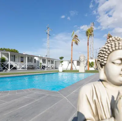 a statue sitting next to a swimming pool at Bungalows Buda Beach in Sanlúcar de Barrameda