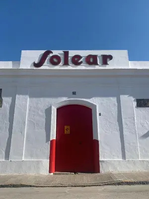 a red door in a white building with a sign at Casa Miguel - Apartamento 5 in Sanlúcar de Barrameda