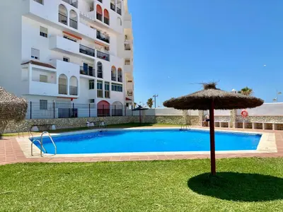 an umbrella and a swimming pool in front of a building at ESTUDIO BLEGAMAR TERRAZA - Playa, WiFi y Aparcamiento in El Puerto de Santa María