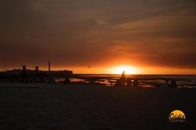 a group of people on the beach at sunset at Casa Capuchinos - FREE PARKING by Cadiz Time in Cádiz