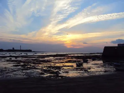 a beach with a sunset in the background at Apartamentos El BALNEARIO by Cadiz4Rentals in Cádiz