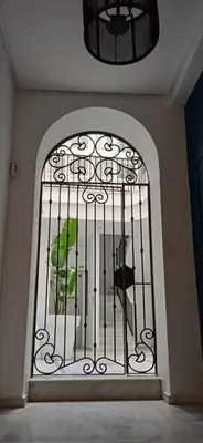 an iron gate with a green bird sitting inside at El 2 de Flamenco Ático 3ºA in Cádiz