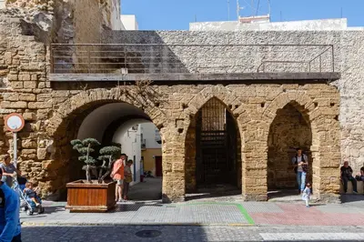 a stone building with arches and people walking around at Atico del Buen CANTAOR by Cadiz4Rentals in Cádiz